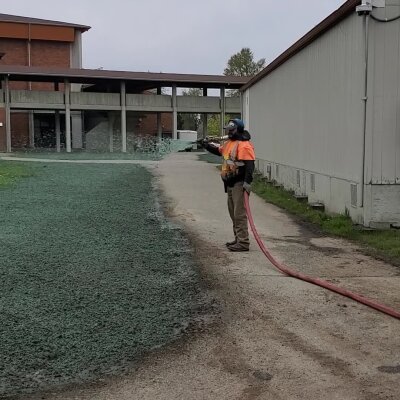 Worker applying hydroseed mixture for grass growth outdoors.
