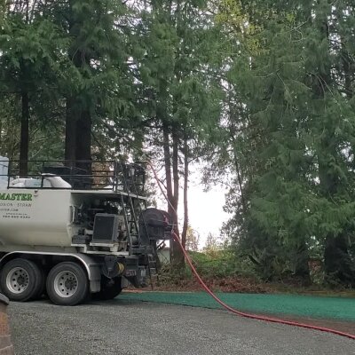 Hydroseeding truck with hose in a wooded area.