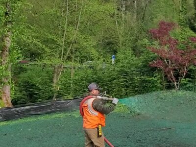 Worker applying hydroseed mixture on lawn in Washington State.