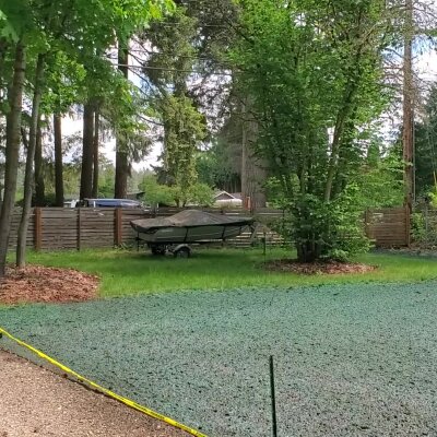 Freshly hydroseeded lawn with trees and a covered boat in Washington state.