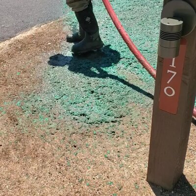 Hydroseeding process with green mulch and worker boots near post.