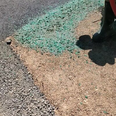 Hydroseeding process with green slurry on soil by worker in boots.