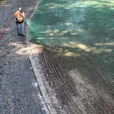 Worker applying hydroseed mixture to residential lawn.