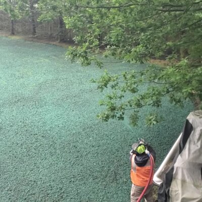 Hydroseeding technician spraying green mixture on lawn in Washington state.