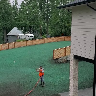 Worker applying hydroseed on residential lawn in Washington.