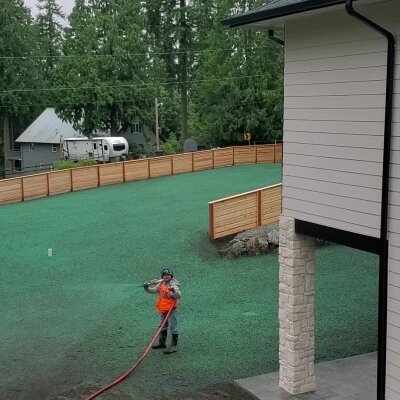 Worker applying hydroseed to lawn in Washington state.