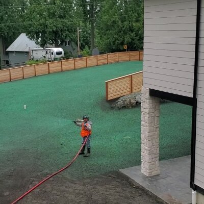 Worker applying hydroseed mix to residential lawn in Washington state.