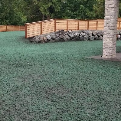 Freshly hydroseeded lawn with a wooden fence and stone column in Washington State.