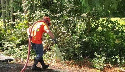 Hydroseeding technician applying mixture on lawn in Washington State.