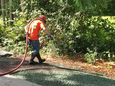 Hydroseeding technician applying mixture on lawn in Washington State.