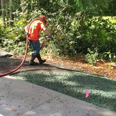 Hydroseeding technician applying mixture on lawn in Washington State.