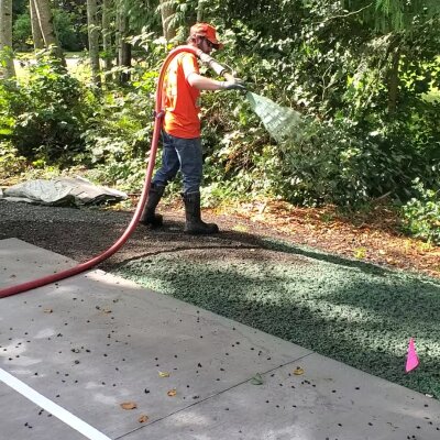 Worker applying hydroseed mix for lawn installation in Washington state.