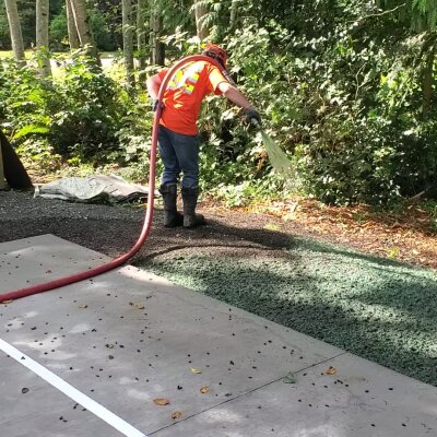 Hydroseeding technician applying slurry to lawn in Washington state.