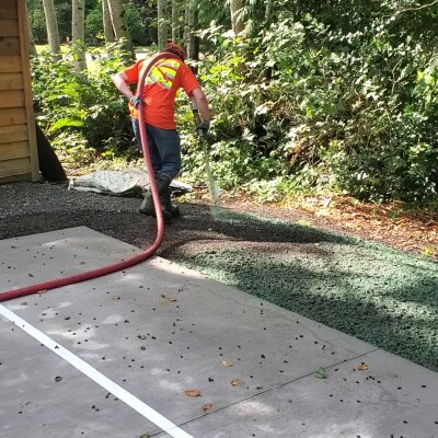 Worker applying hydroseed mix on residential lawn in Washington.