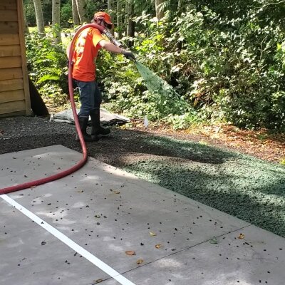 Worker applying hydroseed mixture at a residential site.