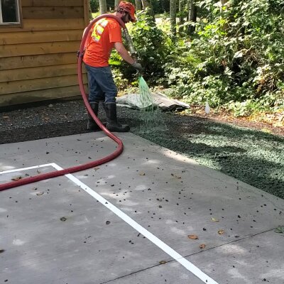 Worker applying hydroseed mixture for lawn installation.